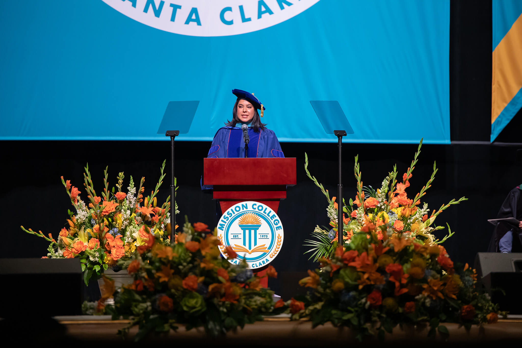 Seher Awan speaking at a podium during commencement ceremony 